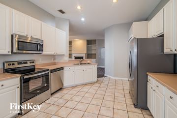 Orange Park house for rent - A kitchen with white cabinets and a black refrigerator.