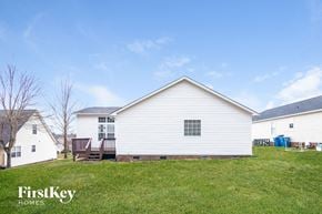 Concord house for rent - A white house with a porch and a deck is surrounded by a grassy yard.
