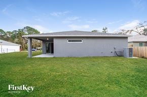 Palm Bay house for rent - a small white house with a grass yard and a backdoor