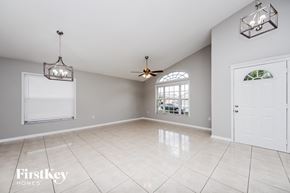 Orlando house for rent - A spacious room with a ceiling fan and a window with a view of a living room.