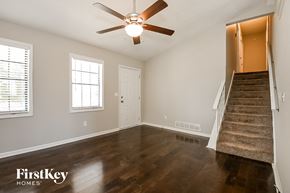 Flowery Branch house for rent - an empty living room with a ceiling fan and a staircase