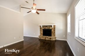 Flowery Branch house for rent - a living room with a stone fireplace and a ceiling fan