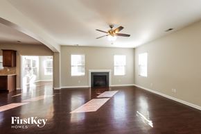 Charlotte house for rent - A spacious living room with a fireplace and a ceiling fan.