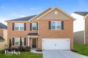 Greensboro house for rent - A brick house with a black garage door and a white garage door.