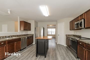 Greensboro house for rent - A kitchen with wooden cabinets and a black fridge.