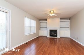 Hamilton house for rent - A well-lit, empty room with a fireplace and wooden floors.