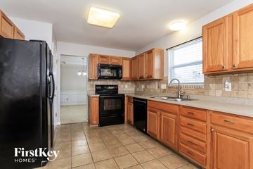 Hamilton house for rent - A kitchen with wooden cabinets and a black fridge.