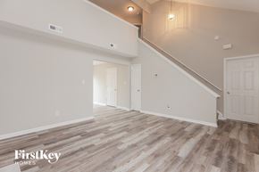 Charlotte house for rent - A spacious room with wooden flooring and a staircase leading to another room.
