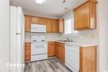 Charlotte house for rent - A kitchen with wooden cabinets and white appliances.