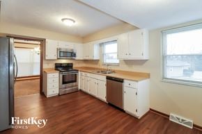 West Chester house for rent - a kitchen with white cabinets and a wooden floor and a stove and refrigerator
