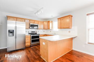 Clemmons house for rent - a kitchen with wooden cabinets and a stainless steel refrigerator