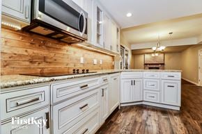 Saint Peters house for rent - a kitchen with white cabinets and a wooden wall