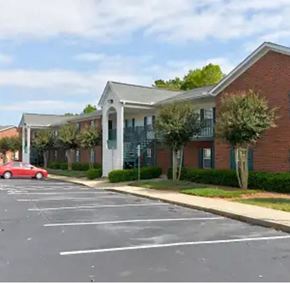 Youngsville apartment for rent - A red car is parked in a parking lot in front of a building.