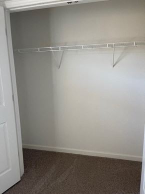 Youngsville apartment for rent - A white door is on the left side of a room with a white wall and a white closet rod.