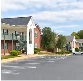 Youngsville apartment for rent - A car is parked in a parking lot in front of a building with a white porch.