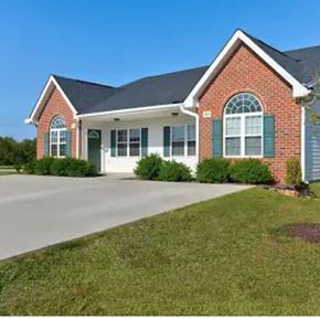 Youngsville apartment for rent - A red brick house with green shutters and a white garage door.