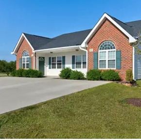Youngsville apartment for rent - A red brick house with green shutters and a white garage door.