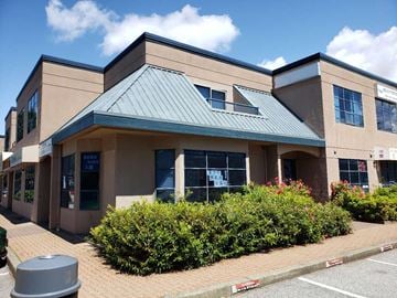 Richmond apartment for rent - A building with a green roof and a parking lot in front.