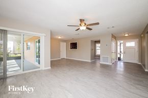 Poinciana house for rent - an empty living room with a ceiling fan and sliding glass doors