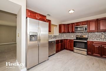 Poinciana house for rent - a kitchen with stainless steel appliances and cherry cabinets