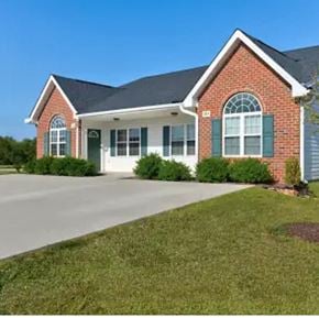 Youngsville apartment for rent - A red brick house with green shutters and a white garage door.