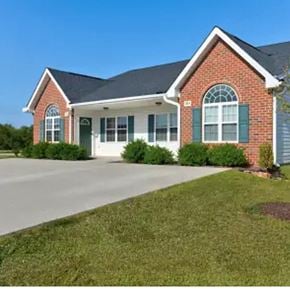 Youngsville apartment for rent - A red brick house with green shutters and a white garage door.