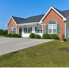 Youngsville apartment for rent - A red brick house with green shutters and a white garage door.