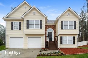 Loganville house for rent - A two-story house with a garage on the first floor and a staircase leading to a door on the second floor.