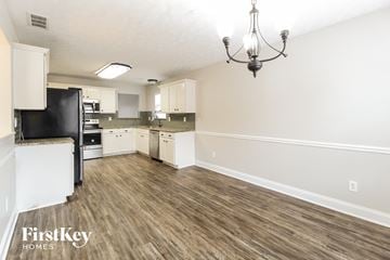 Loganville house for rent - A kitchen with a black fridge and wooden floors.