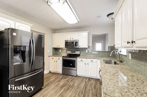 Loganville house for rent - A kitchen with a black fridge and wooden floors.