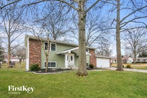 Maryland Heights house for rent - A house with a green and white exterior is surrounded by bare trees.