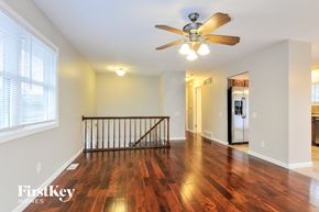 Maryland Heights house for rent - A spacious room with a wooden floor and a ceiling fan.
