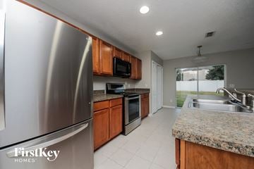 Winter Garden house for rent - A kitchen with a stainless steel refrigerator and wooden cabinets.