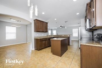 Saint Cloud house for rent - a kitchen with wooden cabinets and tile floors and a stainless steel refrigerator
