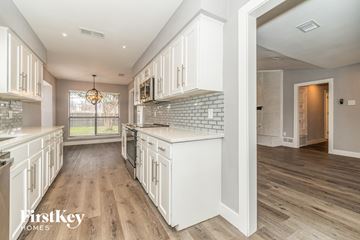 Carrollton house for rent - A kitchen with white cabinets and a wooden floor.