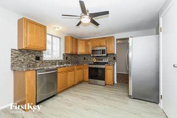 Reynoldsburg house for rent - A kitchen with wooden cabinets and a stone countertop.