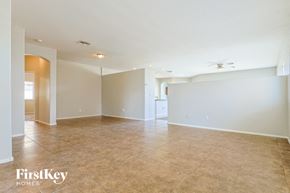 San Tan Valley house for rent - A spacious room with beige tiled flooring and white walls, with a ceiling fan and a doorway leading to another room.