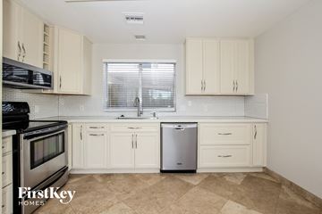 Glendale house for rent - A kitchen with white cabinets and a black fridge.