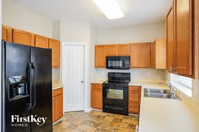 Jamestown house for rent - a kitchen with wooden cabinets and a black refrigerator