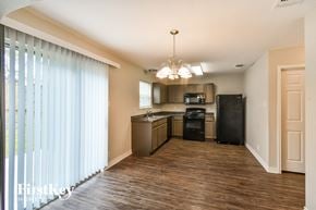 San Antonio house for rent - a kitchen with black appliances and a wood flooring and a window