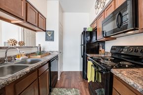 Cincinnati apartment for rent - a kitchen with black appliances and wooden cabinets and a black stove top oven