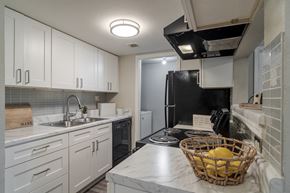 Norcross apartment for rent - a kitchen with white cabinets and black appliances and a basket of fruit
