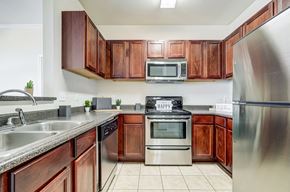 Slidell apartment for rent - a kitchen with stainless steel appliances and wooden cabinets