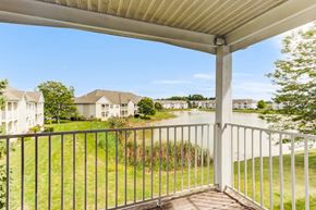 Portage apartment for rent - A balcony with a metal railing overlooks a grassy area and houses.