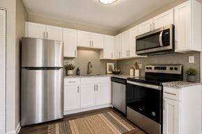 Owings Mills townhouse for rent - A modern kitchen with white cabinets and stainless steel appliances.