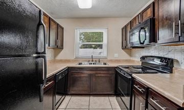 Tampa townhouse for rent - A kitchen with a black refrigerator and black stove top oven.