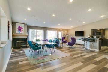 Novi apartment for rent - A modern living room with a fireplace and a dining table set up.
