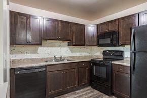 Novi apartment for rent - A kitchen with dark wood cabinets and black appliances.