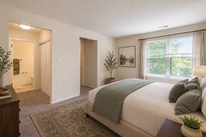 Olney apartment for rent - A bedroom with a large bed and a window overlooking trees.