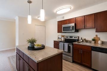 Olney apartment for rent - A kitchen with brown cabinets and a granite countertop.